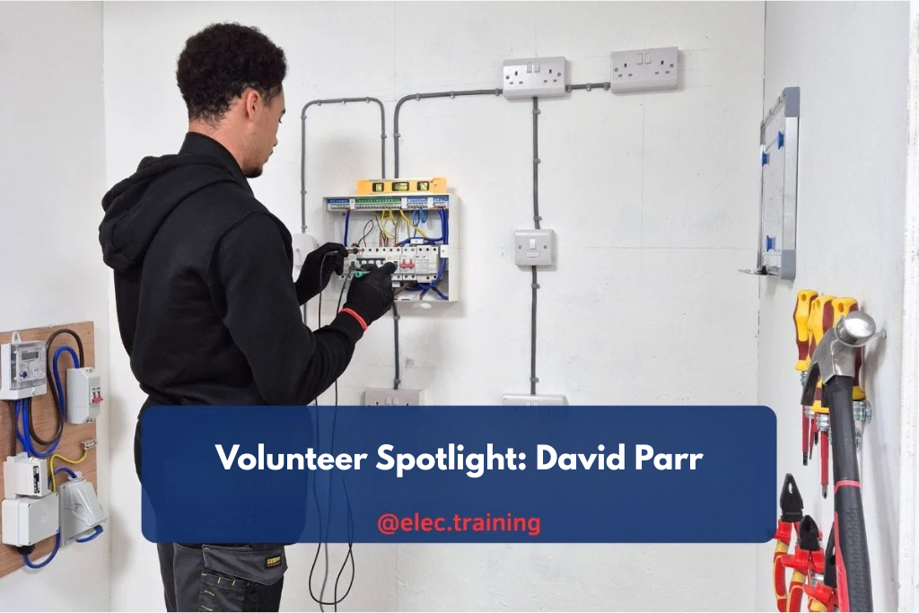 Electrician testing a consumer unit on a training wall with conduit and sockets